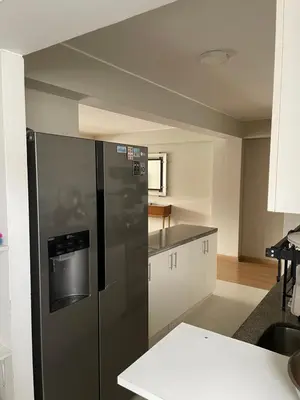 a kitchen with a black refrigerator and white cabinets at Departamento 17 personas San Isidro in Lima