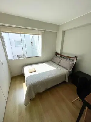 a small bedroom with a bed and a window at Departamento 17 personas San Isidro in Lima