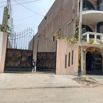 a person standing in front of a building with gates at Hostal Luren in Nazca