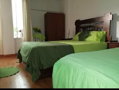 a bedroom with two beds with green sheets at Hotel Conquistadores Inn in Ica