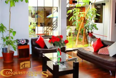 a living room with couches and a glass table with flowers at Hotel Conquistadores Inn in Ica