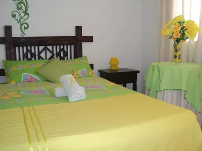 a bedroom with a yellow bed with a vase of flowers at Hotel Conquistadores Inn in Ica