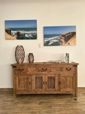 a wooden dresser in a room with three pictures on the wall at Casa Z Paracas in Paracas