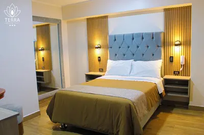 a bedroom with a large bed with a blue headboard at Terra Premium Hotel in Huánuco