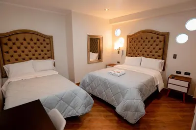 a hotel room with two beds and a table at Hotel Melthon Urbans in Ayacucho
