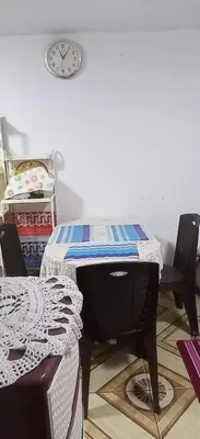 a table with two chairs and a clock on the wall at LA POSADA CHASQUI Perú in Lima