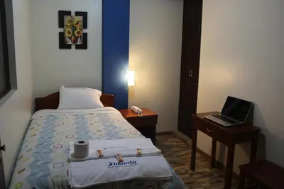 a bedroom with a bed and a laptop on a table at Hostal Inkanto Taruma in Tarma