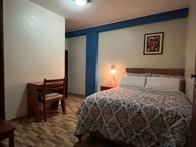 a bedroom with a bed and a desk and a chair at Hostal Inkanto Taruma in Tarma
