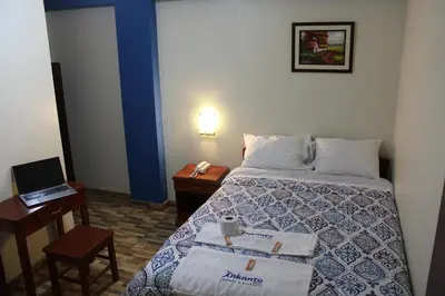 a hotel room with a bed and a table with a laptop at Hostal Inkanto Taruma in Tarma