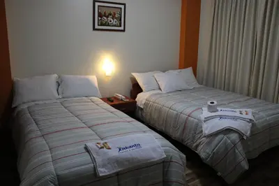 two beds in a hotel room with towels on them at Hostal Inkanto Taruma in Tarma