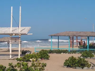 a beach with a pool and umbrellas and the ocean at Hamacas in Punta Negra