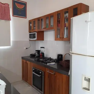 a kitchen with wooden cabinets and a white refrigerator at CASA DE PLAYA Durante todo el año in Punta Negra
