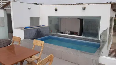 a house with a swimming pool with a wooden table and a table sidx at CASA DE PLAYA Durante todo el año in Punta Negra