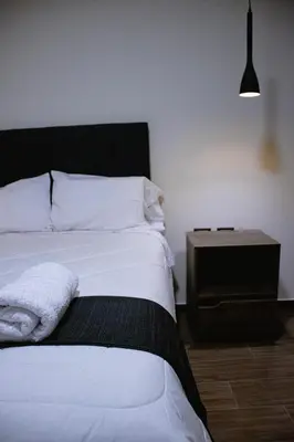 a bedroom with a white bed and a night stand at PRANA HOTEL LOUNGUE BAR in Huancayo