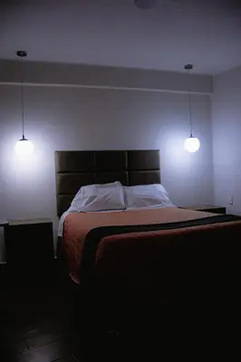a bedroom with a bed with two lights on it at PRANA HOTEL LOUNGUE BAR in Huancayo