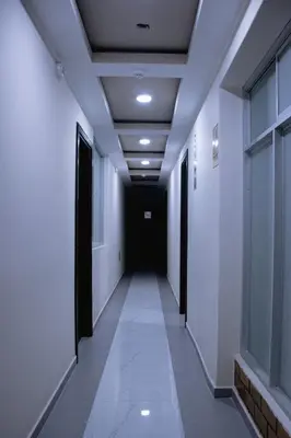 a corridor in an office building with white walls and a black door at PRANA HOTEL LOUNGUE BAR in Huancayo