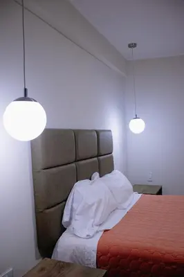 a bedroom with a bed with two lights above it at PRANA HOTEL LOUNGUE BAR in Huancayo