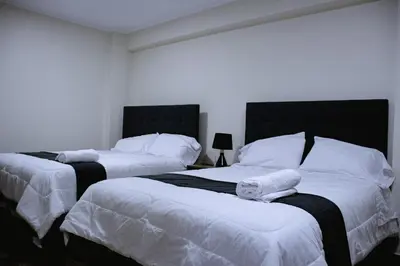 two beds in a bedroom with white sheets and pillows at PRANA HOTEL LOUNGUE BAR in Huancayo