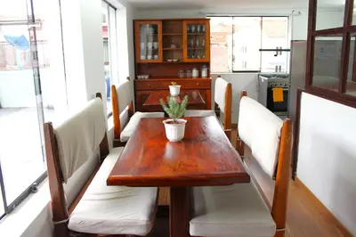 a dining room with a wooden table and white chairs at Inti Wasi in Cusco