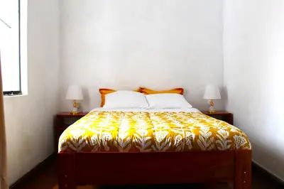 a bedroom with a bed with a yellow and white bedspread at Inti Wasi II in Cusco
