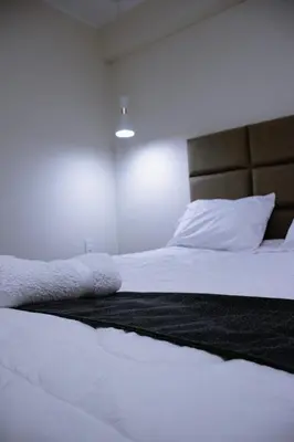 a bedroom with a white bed with a brown headboard at PRANA in Huancayo