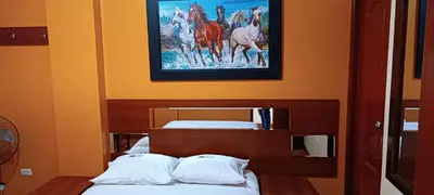a bedroom with two beds and a painting of horses at Hotel Allison in Huacho
