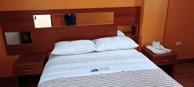 a bed with white sheets and pillows in a room at Hotel Allison in Huacho