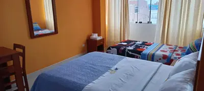 a hotel room with two beds and a mirror at Hotel Allison in Huacho