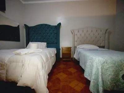 a bedroom with two beds with white sheets and a blue headboard at HOSTAL TOSCANO SUITES in El Tambo