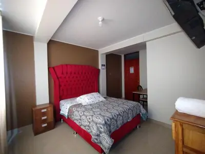 a bedroom with a red bed with a red headboard at HOSTAL TOSCANO SUITES in El Tambo