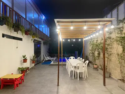 a patio with a table and chairs and lights at Villa Alfonso - Casa playa con piscina temperada in Lima