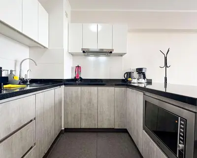 a kitchen with white cabinets and black counter tops at Peruvian Apartments Barranco 1606 in Lima