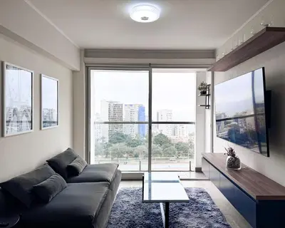a living room with a couch and a large window at Peruvian Apartments Barranco 1606 in Lima