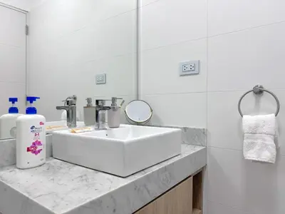 a white bathroom with a sink and a mirror at Peruvian Apartments Barranco 1609 in Lima