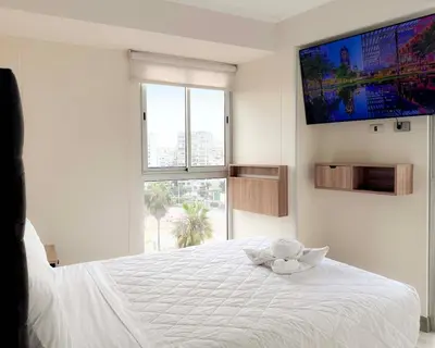 a bedroom with a white bed with a flat screen tv at Peruvian Apartments Barranco 904 in Lima