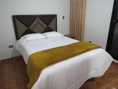 a bedroom with a large white bed with a gold blanket at Hospedaje EL RINCONCITO II - Cerca al Aeropuerto Jauja in Jauja