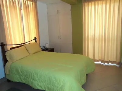 a bedroom with a green bed with two pillows at Sol de Paracas Apart Hotel Pisco in Pisco