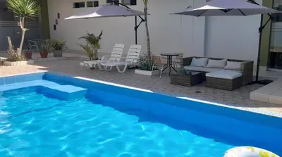 a blue swimming pool with chairs and umbrellas at Sol de Paracas Apart Hotel Pisco in Pisco