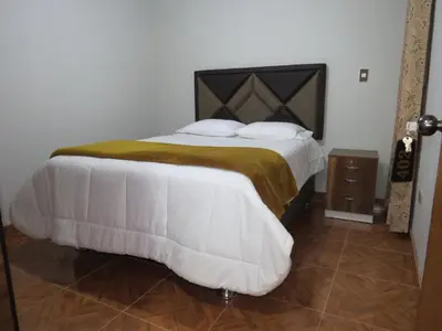 a bedroom with a large bed with white sheets and pillows at DEPARTAMENTO-Hospedaje EL RINCONCITO II 100m2, 3hab, 4baños, sala, comedor, cocina in Jauja