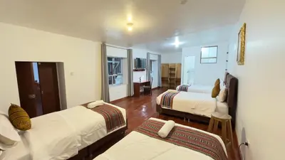 a room with two beds and a living room at Casona Libertrek Inn in Cusco