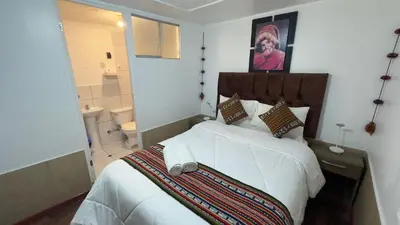a bedroom with a large white bed and a bathroom at Casona Libertrek Inn in Cusco