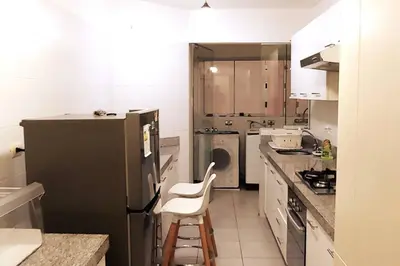 a kitchen with a black refrigerator and a stool in it at Excellent apartment, access to pool, grills, ballroom in Lima