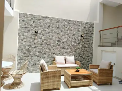 a living room with rattan furniture and a stone wall at Hotel Sunlight in Paracas