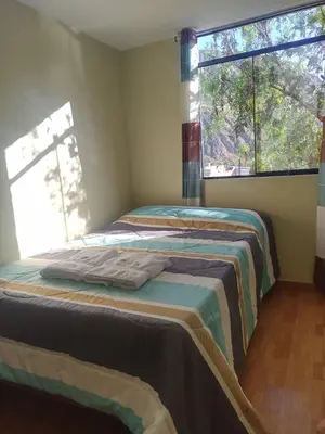 a bedroom with two beds and a window at Hotel El Gran Valletero in Cotahuasi