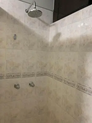 a bathroom with a shower with beige tiles at Grand Hotel Betsy in Lima