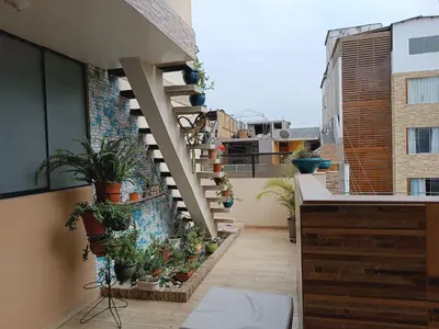 a balcony with potted plants and stairs on a building at Acogedor APT a 20 min Aeropuerto in Lima