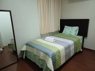 a small bedroom with a bed with a mirror at Habitación acogedora Orué in Lima