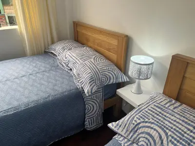 a bedroom with two beds and a table with a lamp at San Miguel, lindo depa, 3 camas, internet y cable in Lima