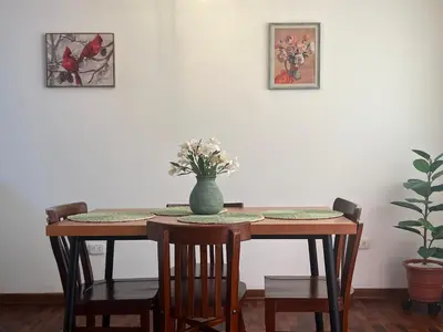 a dining room table with a vase of flowers on it at San Miguel, lindo depa, 3 camas, internet y cable in Lima