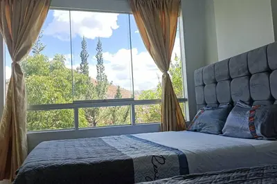 a bed in a bedroom with a large window at Qori Garden Apartment in Cusco
